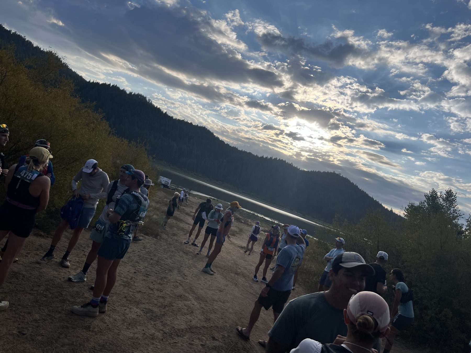 Runners lined up at the Spooner Lake start line at dawn, sun over the ridge above the water